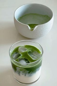 two glasses filled with green liquid next to each other