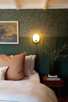 a bed with two pillows and some pictures on the wall above it in a bedroom