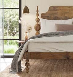 a bed with white sheets and pillows in a room next to a wooden headboard