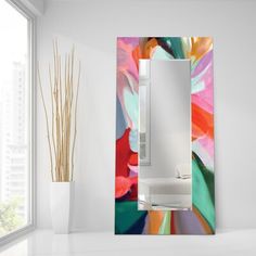 a white toilet sitting under a bathroom mirror next to a vase with flowers on it