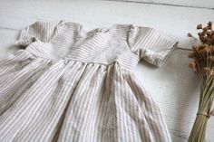 2-3 WEEK TURNAROUND TIME. This tan and cream striped cotton/linen handmade dress is the perfect addition to any little's wardrobe! Though great for all year cuteness! Perfect fall and winter with elbow length sleeves. Or summertime fun with the tank version. Dress is a elbow-sleeved or sleeveless, with a lined, slightly curved front bodice. Three wooden button closures in the back of the dress of the 3/4 sleeved version. Tank version has a V-back and 1 button. This fabric is a linen cotton blend Cute Fitted Button-up Dress, Cute Short Sleeve Dress With Button Closure, Cute Button-up Dress With Buttons, Cute Daywear Dresses With Buttons, Beige Cotton Dress With Buttons, Cute Cotton Button-up Dress, Cute Button-up Cotton Dresses, Cute White Dresses With Buttons, Cream Cotton Dress With Buttons