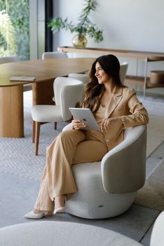 a woman sitting in a chair using a tablet