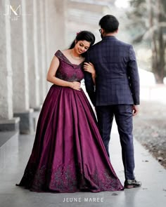 a man in a suit and woman in a purple dress walking down the street together