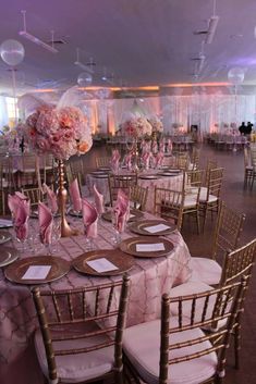 tables and chairs are set up for a formal function with pink flowers in vases