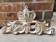 an ornately carved piece of wood sitting on the ground next to a brick wall