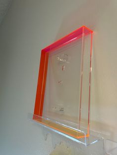 an orange and clear shelf on the wall