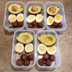 four plastic containers filled with eggs, meatballs and an avocado cut in half