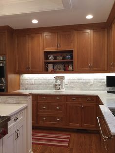 a kitchen with wooden cabinets and white marble counter tops, along with a microwave oven