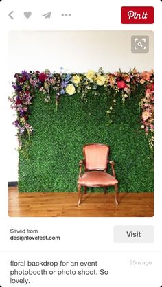 a chair sitting in front of a green wall with flowers and greenery on it