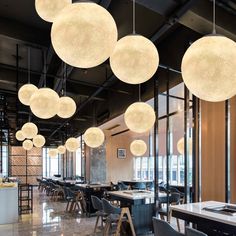 a large room with many lights hanging from it's ceiling and chairs around the tables