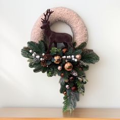 a christmas wreath with an antler and pine cones on it, hanging from the side of a wall