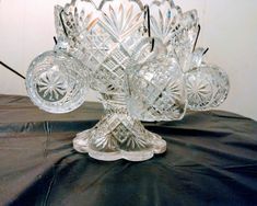 a clear glass vase sitting on top of a black tablecloth covered table next to a white wall