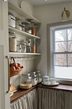 a kitchen with lots of glass jars and containers on the shelves next to a window