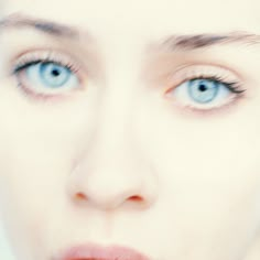 a woman with blue eyes is brushing her teeth