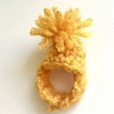 a crocheted pineapple shaped object on a white surface, with the top section partially closed