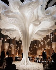 a large white tree in the middle of a room with tables and chairs around it