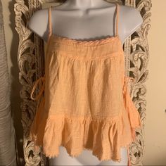 Peach Babydoll Style Tank With Adjustable Straps And Side Ties Cute Ruffled Tank Top For Spring, Cute Spring Beach Tops, Orange Ruffled Top For The Beach, Orange Ruffled Top For Beach, Orange Cotton Tank Top For Spring, Peach Tops For Summer Brunch, Peach Cotton Tops For Brunch, Cute Orange Beach Tops, Spring Peach Cotton Tank Top