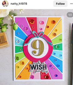 a card with the number nine on it next to a pen and some paper flowers