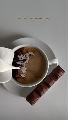 there is a cup of coffee on the saucer next to a spoon and chocolate bar