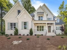 a large white house with lots of windows in the front yard and landscaping around it