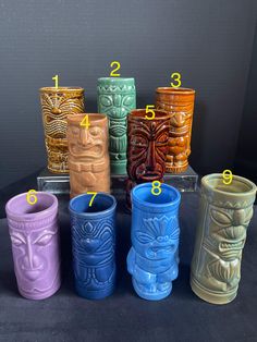 a group of different colored vases sitting on top of a black table next to each other