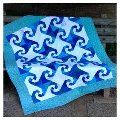 a blue and white quilt sitting on top of a wooden bench