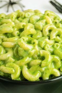 a black bowl filled with green macaroni and cheese