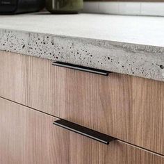 a kitchen counter top with two black handles on the bottom and an oven in the background