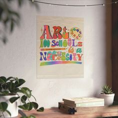 an art poster hanging on the wall above a table with books and plants in front of it