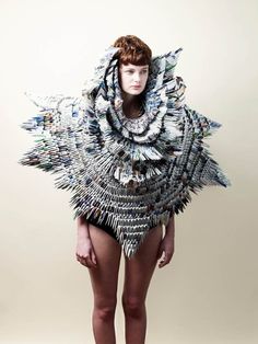 a woman in a bodysuit made out of paper and metal chains, with her hands on her hips