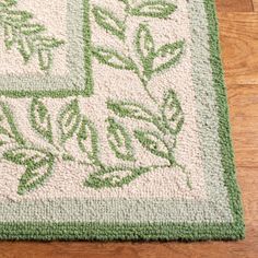 a green and white rug on the floor with leaves drawn on it's sides