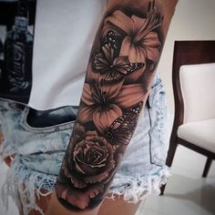 a woman's arm with black and white tattoos on it, flowers and butterflies