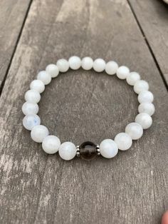 the white beaded bracelet with black crystal beads is displayed on a wooden table next to a