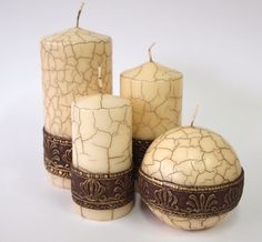 four white candles sitting next to each other with brown trim around them on a white surface