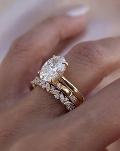 a woman's hand with a gold ring and two diamond engagement rings on it