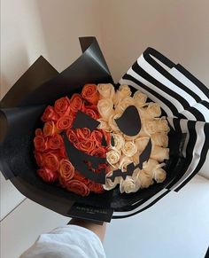 a black and white hat with roses in the shape of a skull is held by a woman's hand