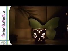 a lit up vase sitting on top of a table next to a butterfly shaped wall