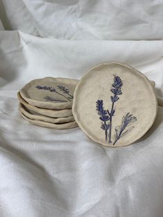 four plates with blue flowers on them sitting on a white cloth covered bedding sheet