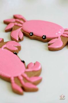 some pink and brown crab cookies on a white table with black dots in the middle