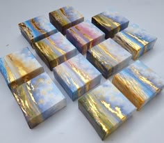 many small boxes are stacked on top of each other with gold and blue paint in them