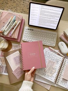 a person is holding a notebook in front of a laptop and papers on a desk