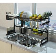 a kitchen sink filled with lots of dishes next to a large window overlooking the city