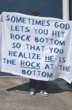 a person holding up a sign that says sometimes god lets you hit rock bottom so that you realize he is the rock at the bottom