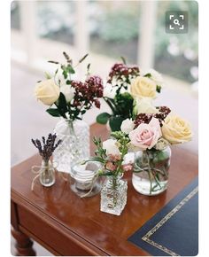 three vases filled with flowers sitting on top of a wooden table