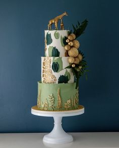 a three tiered cake decorated with giraffes and palm leaves