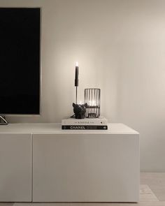 a white table with books and a candle on it in front of a flat screen tv