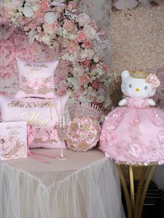 a table topped with pink and white items next to a flower covered wall in the background