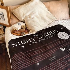 a bed with a blanket and pillows on top of it next to two framed books