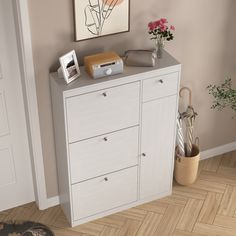 a white cabinet with drawers and pictures on top in a room next to a door