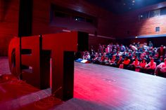 an auditorium full of people with red lighting